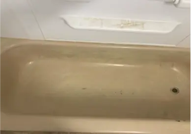 Old bathtub with peeling paint and discoloration before refinishing
